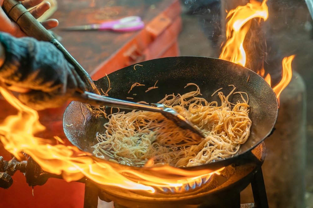 Cooking noodles in a pan with big flames