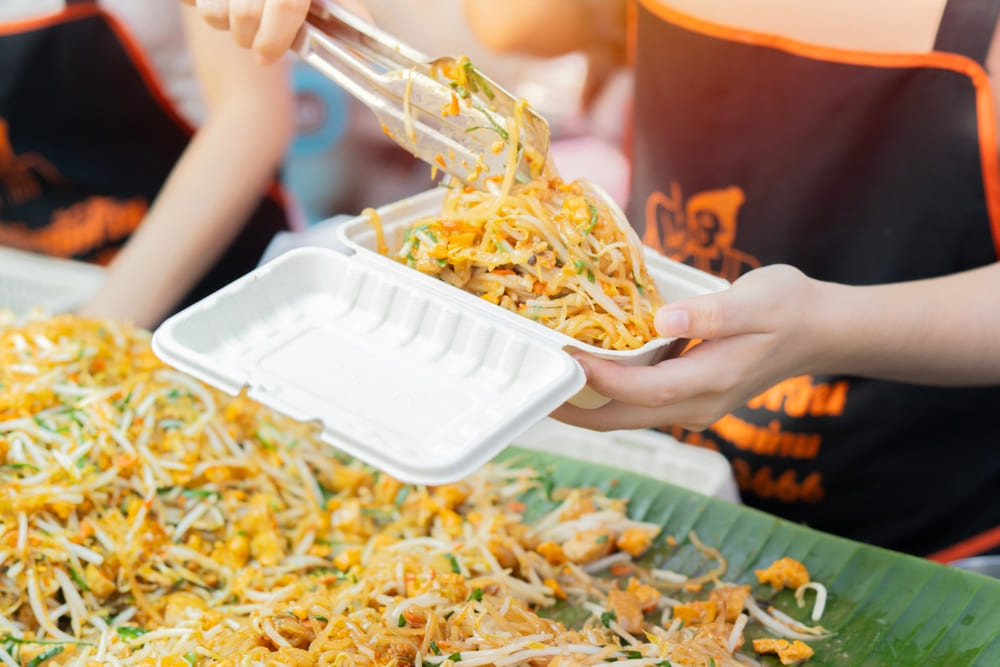 Food vendor serving Pad Thai in a food container