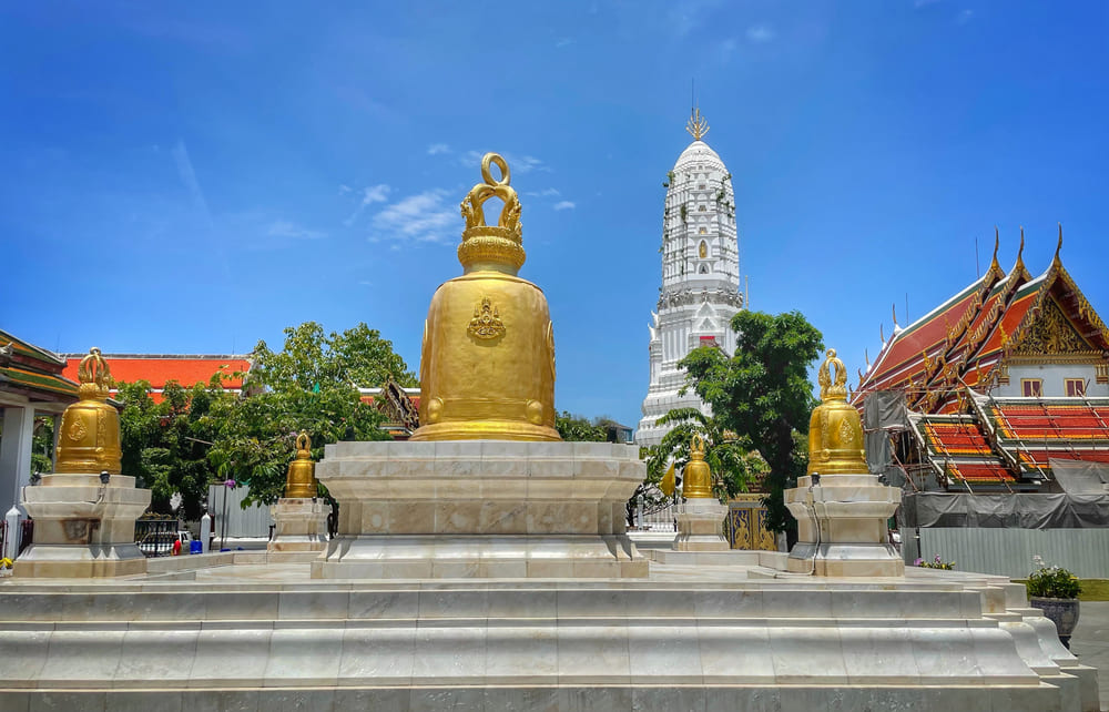 Golden bells with white pagoda in the back at Wat Rakhang Khositaram