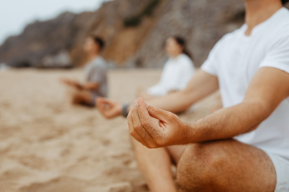 Group of people meditating on the beach