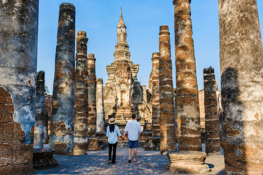 Two travelers walking at Wat Mahathat in Sukhothai Historical Park