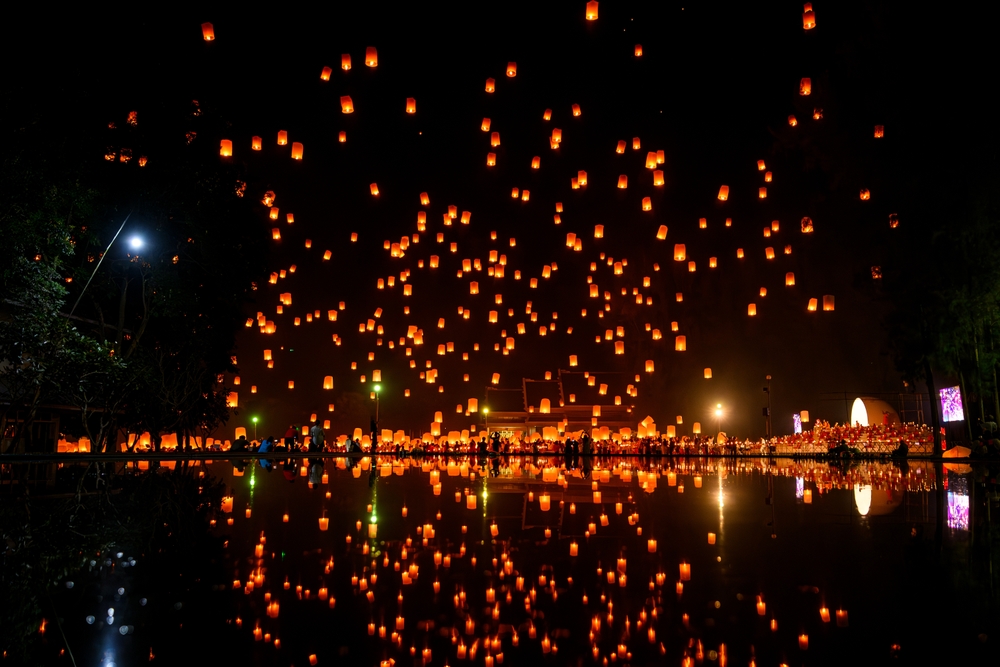Plenty of sky lanterns flying, reflecting on the water