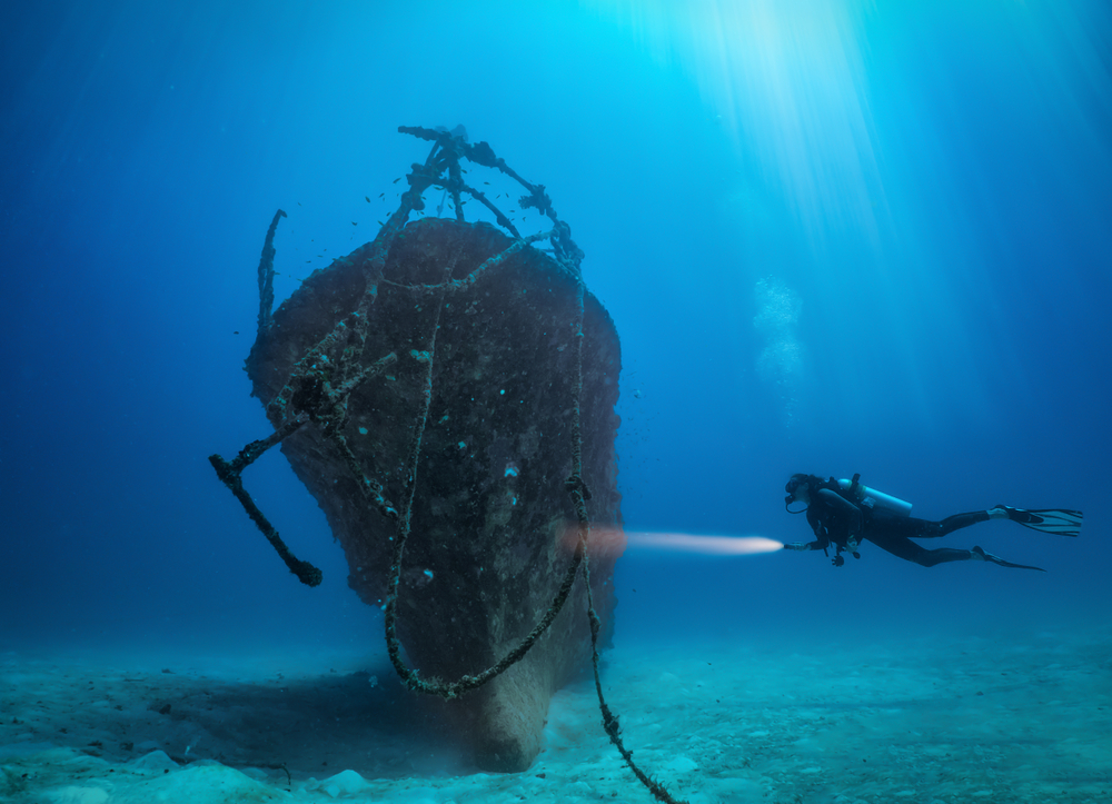 Woman scuba diving and observing the British Loyalty Wreck in the Maldives