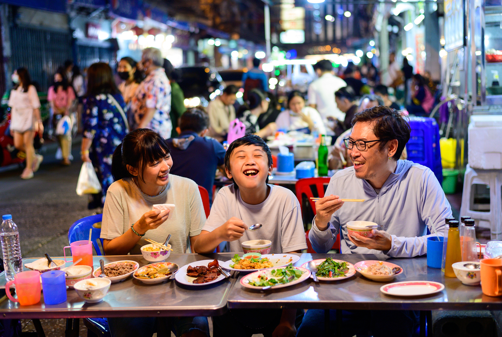 Asian family enjoying street food at Yaowarat Road in Bangkok