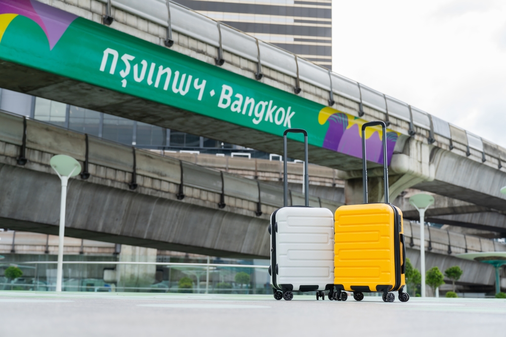 Two luggage on a skywalk in front of Bangkok’s BTS Skytrain tracks