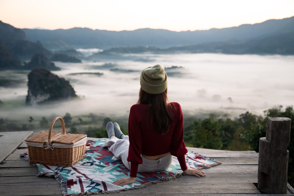 A woman sitting on a balcony surrounded by a foggy mountain view in winter