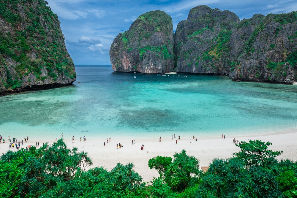 Crystal-clear waters at Maya Bay with visitors on the white sand beach