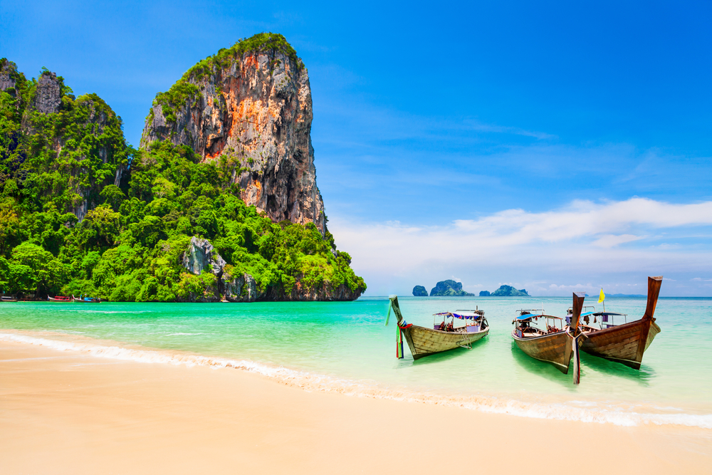 Longtail boats on the beach with limestone cliff in Thailand