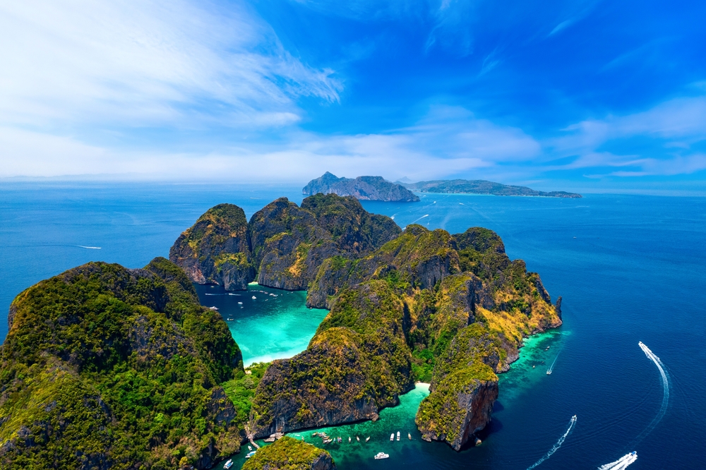 Maya Bay with turquoise lagoon in the middle, surrounded by limestone cliffs and blue Andaman Sea