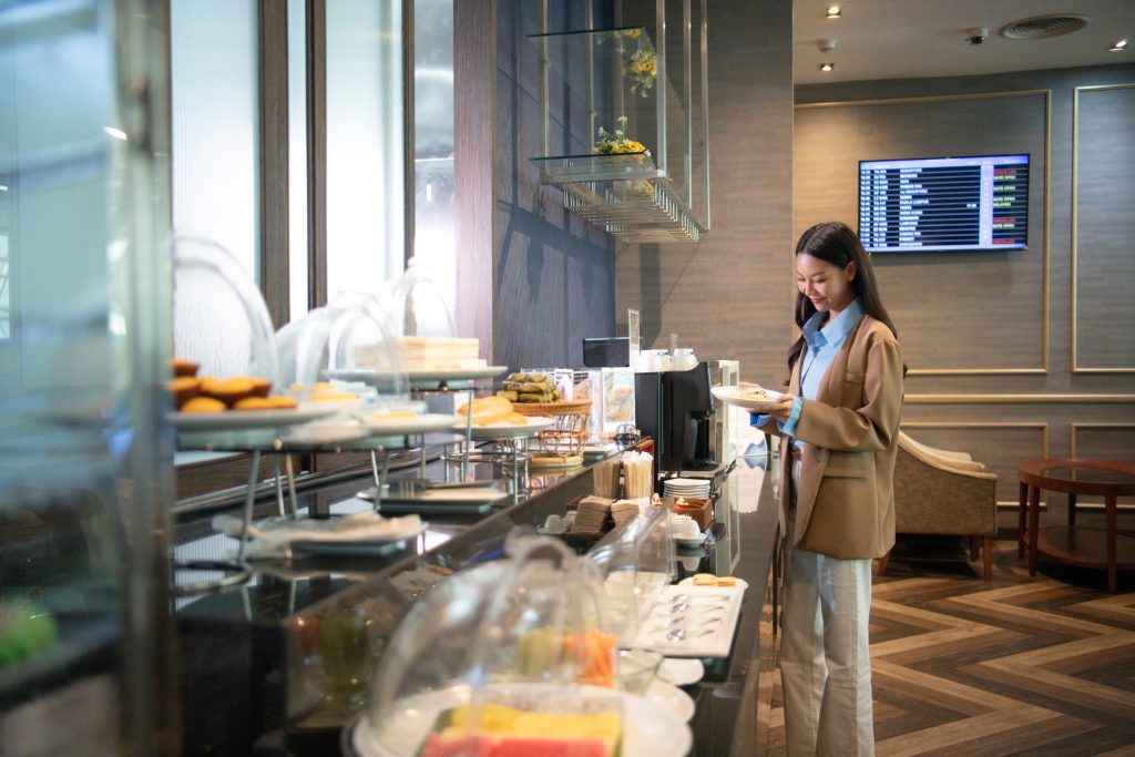 Female traveler selecting gourmet dishes at Bangkok Airways Blue Ribbon Club Lounge.