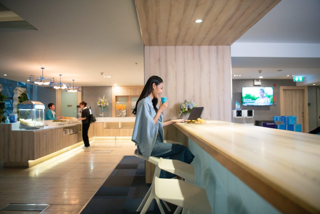 A female traveler working happily while enjoying snacks at the Bangkok Airways Boutique Lounge.