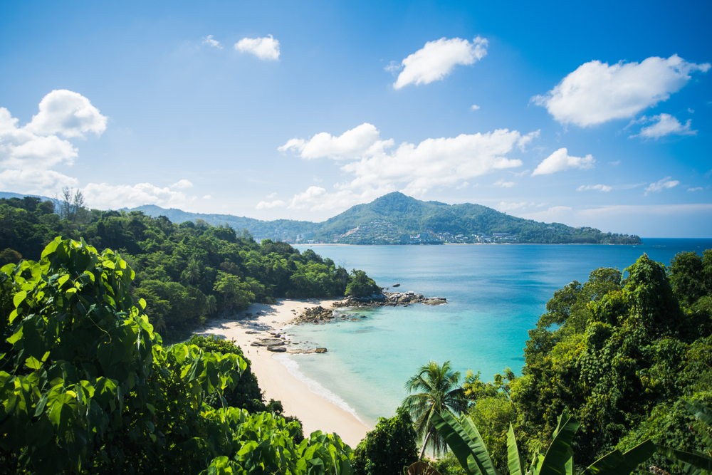 Landscape view of Kamala Beach, Phuket, Thailand, with green jungles and mountains in the background