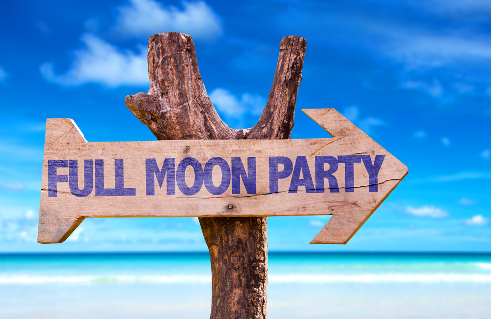 A Full Moon Party wooden sign with beach in the background