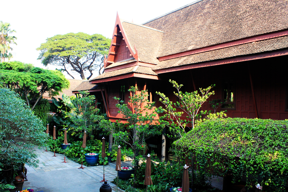 Exterior of a traditional Thai house at Jim Thompson House Museum surrounded by greenery.
