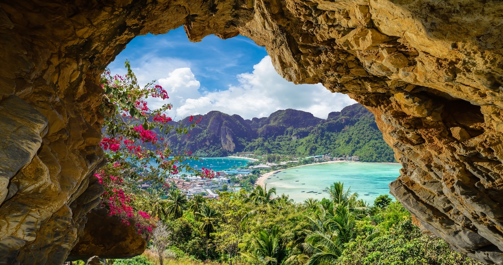 A view of Koh Phi Phi’s blue sea and green mountains through a curved rock formation