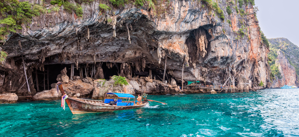 Viking cave under a huge limestone cliff with crystal-clear seawater in Koh Phi Phi