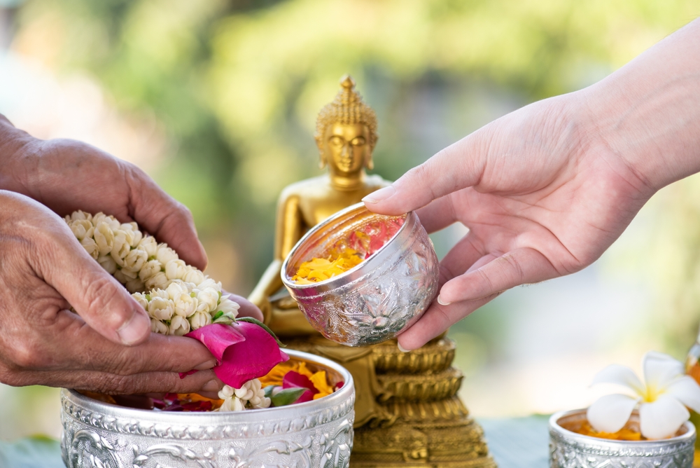 A Rod Nam Dam Hua ritual in front of a small Buddha image during Songkran