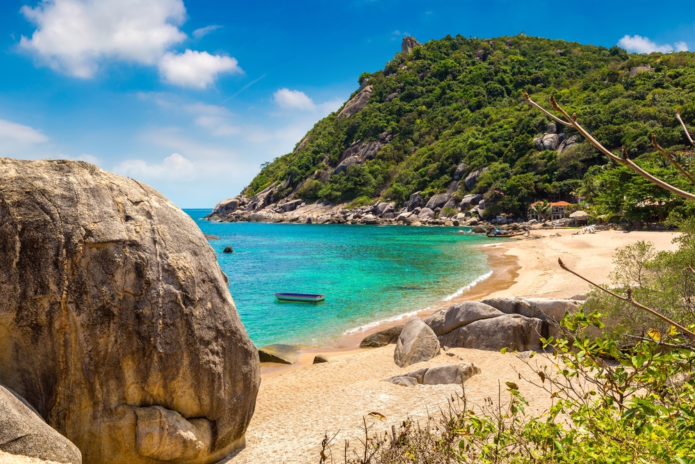 View of Tanote Bay on Koh Tao, with golden beach, green mountains, and clear turquoise waters