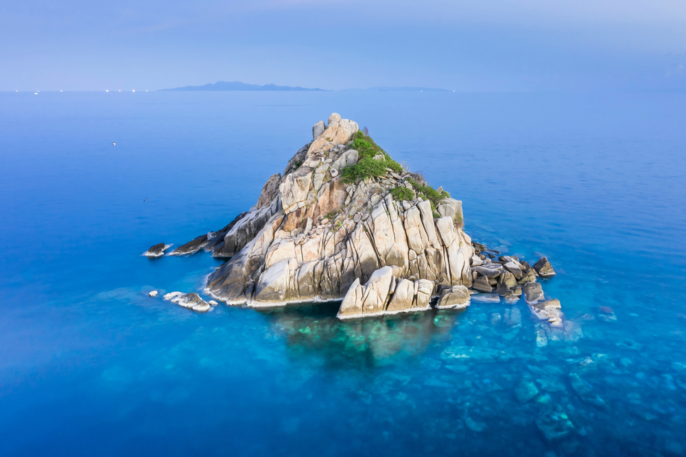 Aerial view of the rocky Shark Island in the middle of the blue ocean in Koh Tao