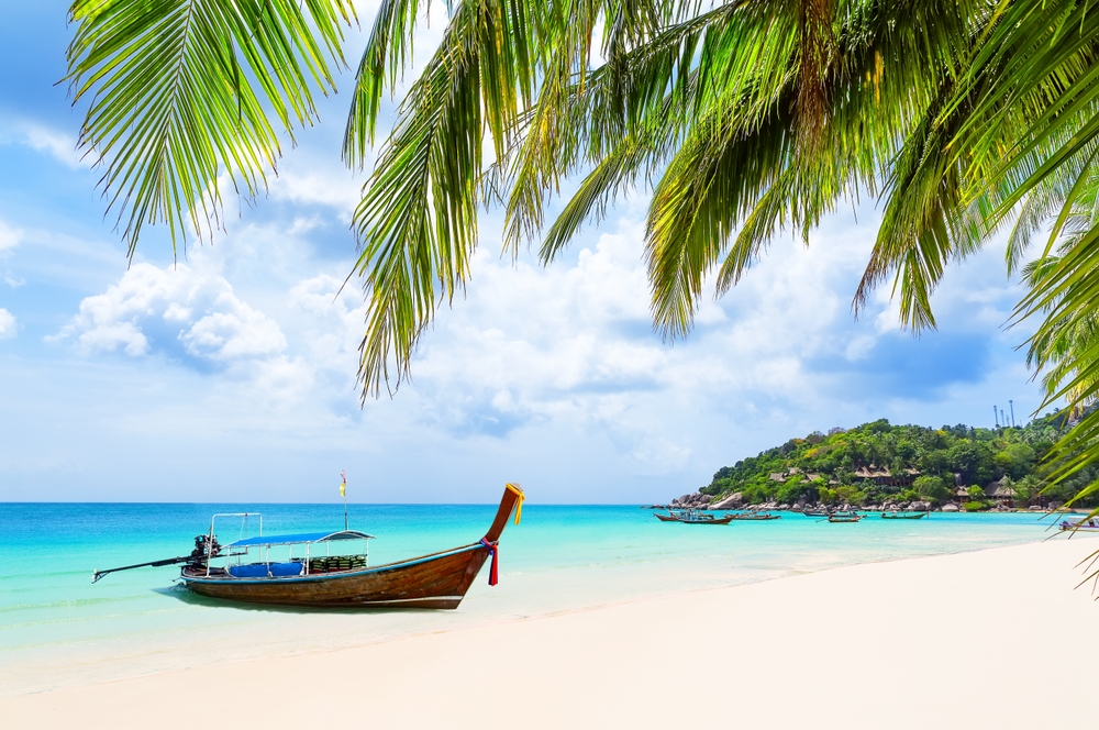 Longtail boat on the white sand beach and clear sea waters in Koh Tao