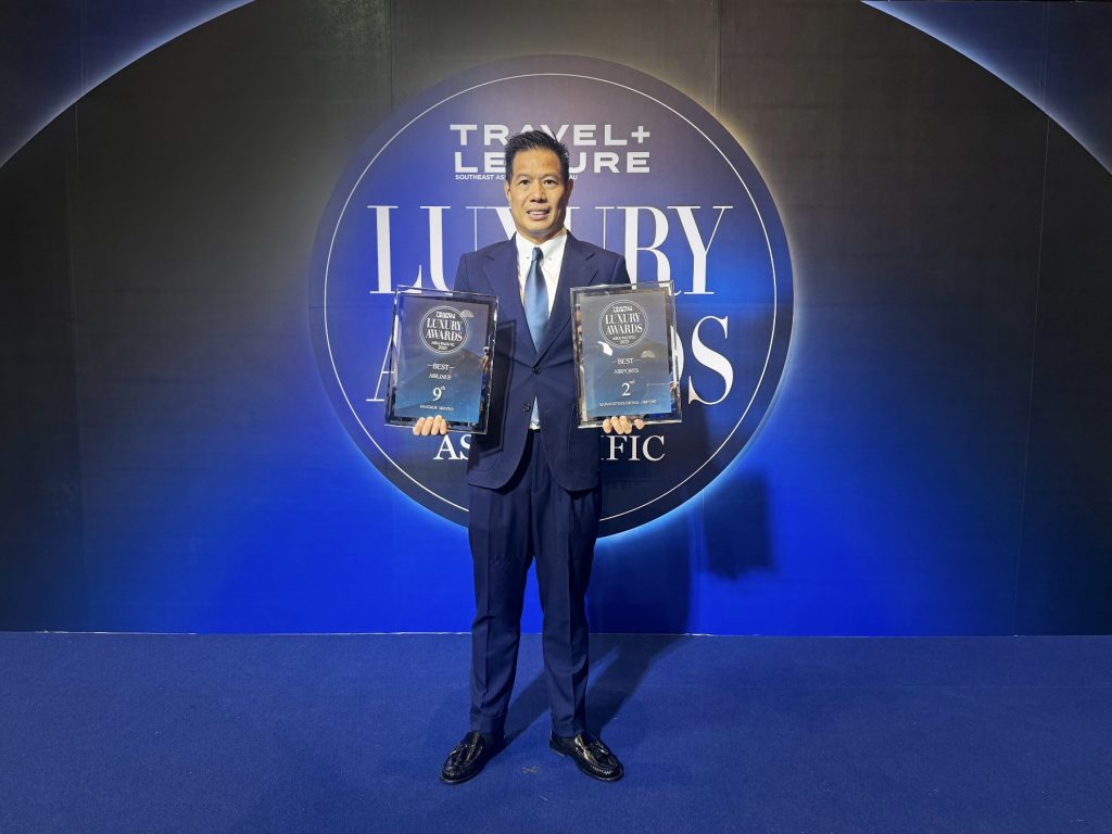 Representative holding Travel + Leisure Luxury Awards plaques for Samui International Airport.