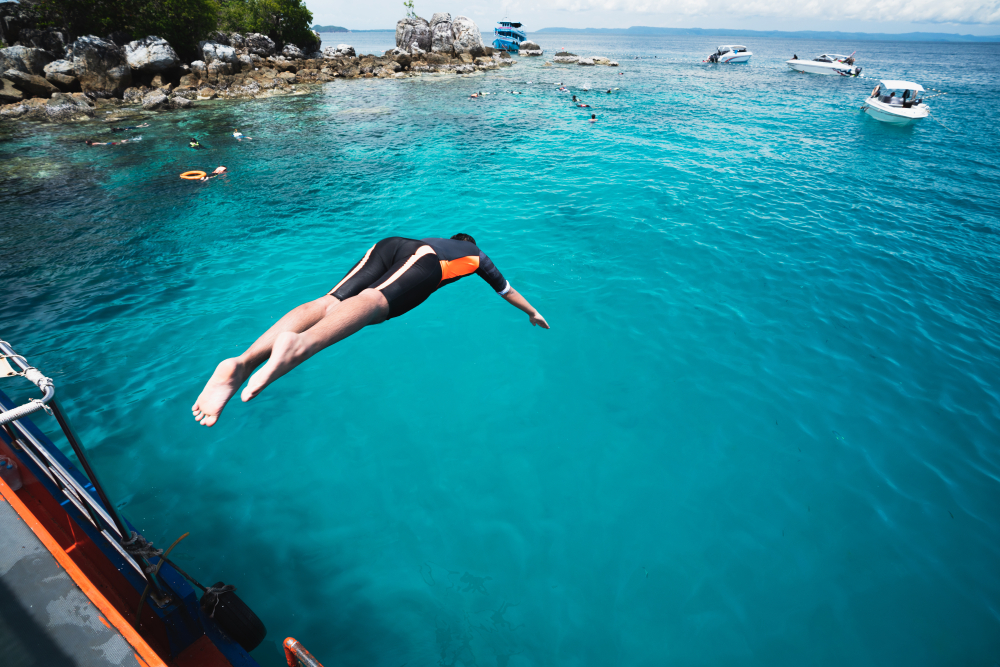 Tourists jumping from a boat to dive in the sea at Koh Rang, Trat Province.