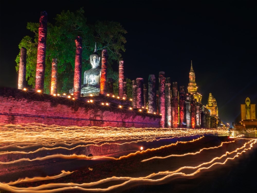 บรรยากาศงานเวียนเทียนรอบโบราณสถาน เสาศิลาแลง และพระพุทธรูปในยามค่ำคืน