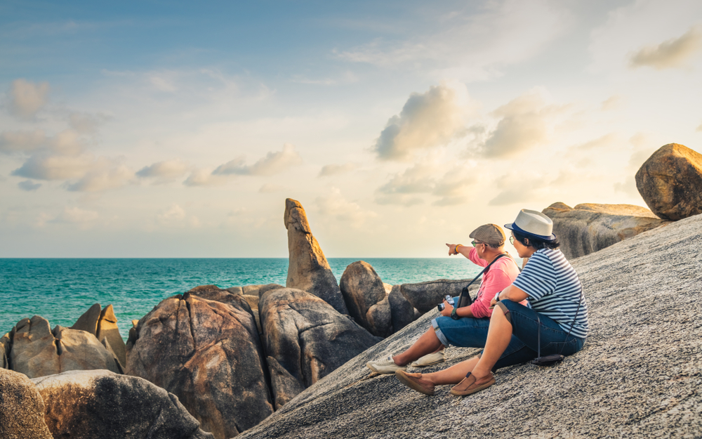 A couple sitting near Hin Ta Hin Yai Rocks on Koh Samui, exploring the best islands in the world.