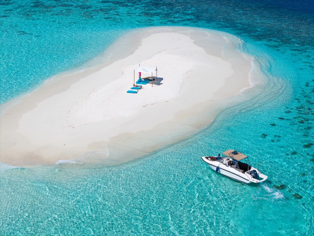 A boat arriving at a pristine white sandbank in the Maldives.