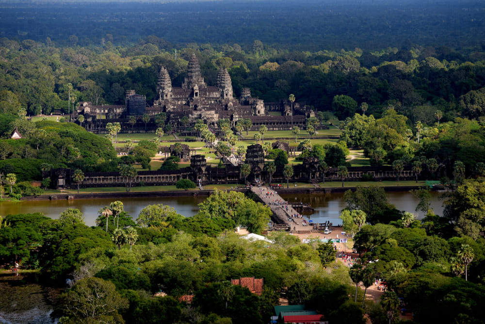 The majestic Angkor Wat temple enveloped by green forests in Siem Reap during the rainy season in Southeast Asia.
