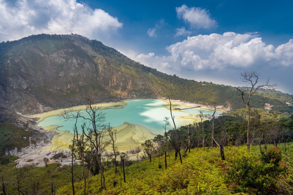 The misty, turquoise Kawah Putih crater lake in Bandung, Indonesia, during the rainy season in Southeast Asia.