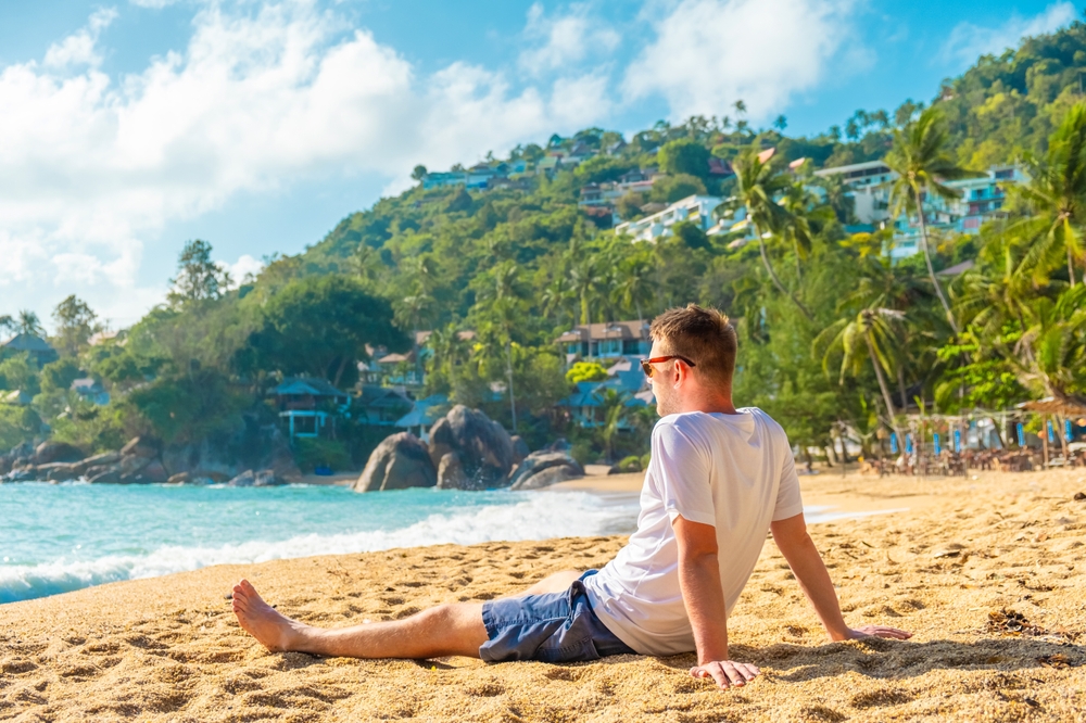 A man relaxing on a sunny sandy beach in Koh Samui, enjoying the best islands in the world.
