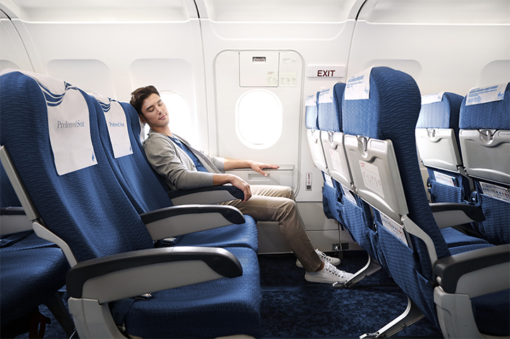 A passenger relaxing on a direct Bangkok Airways flight to Luang Prabang, a convenient start to a Laos travel itinerary.