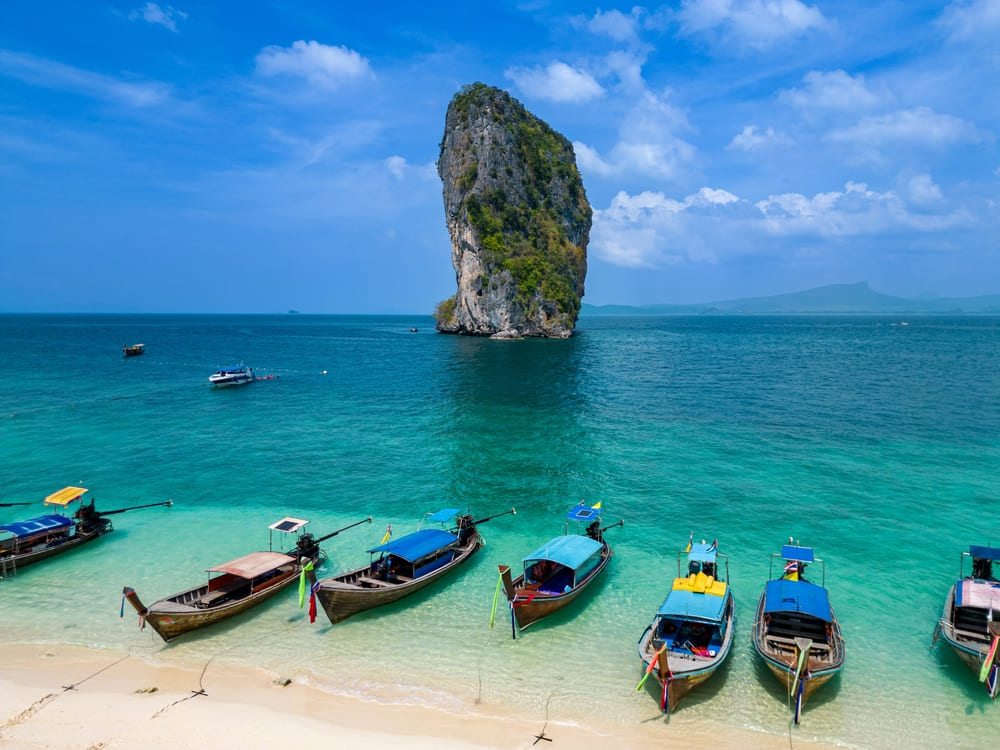เรือหางยาวนำเที่ยวจอดเรียงรายริมหาดทรายขาว คอยให้บริการนักท่องเที่ยวที่เดินทางมาเยือนทริป 4 เกาะ และเกาะปอดะ กระบี่
