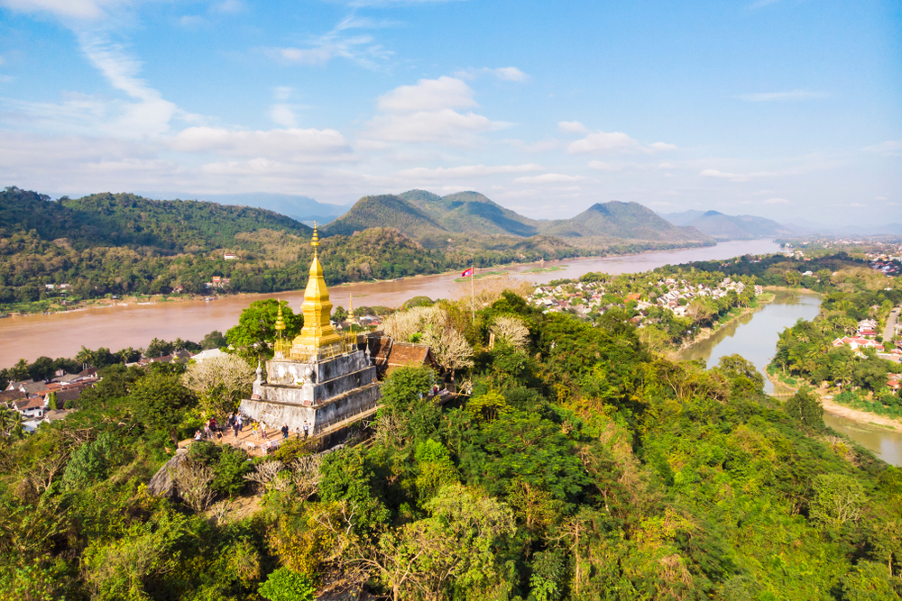 A sunset cruise along the Mekong River in Luang Prabang, showcasing traditional boats and limestone mountains.