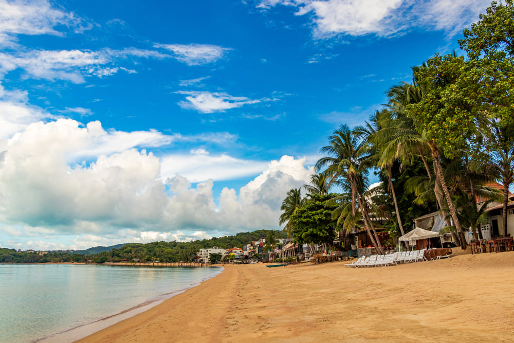 ทิวทัศน์ชายหาดโค้งยาวและดงมะพร้าวที่หาดบ่อผุด แหล่งรวมกิจกรรมทางน้ำใกล้หาดเชิงมน เกาะสมุย