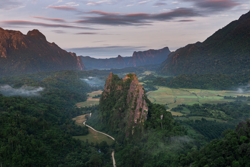 A breathtaking aerial view of limestone mountains and green rice fields from Nam Xay Viewpoint in Vang Vieng.
