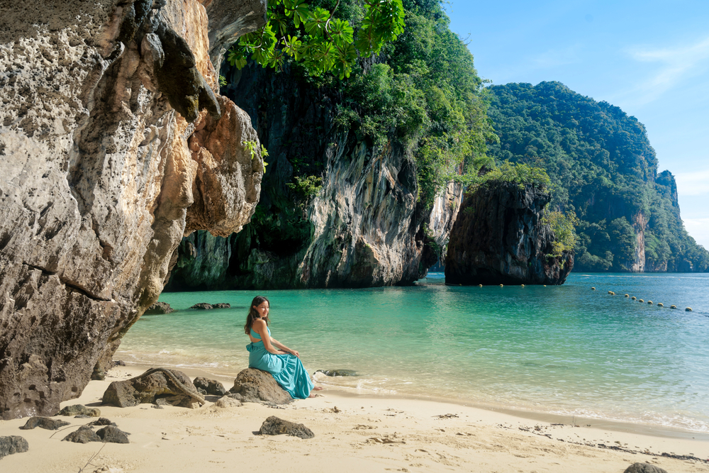 นักท่องเที่ยวหญิงนั่งพักผ่อนริมชายหาดอันเงียบสงบที่เกาะเหลาลาดิง หรือ Paradise Island  ใกล้ทะเลแหวก กระบี่