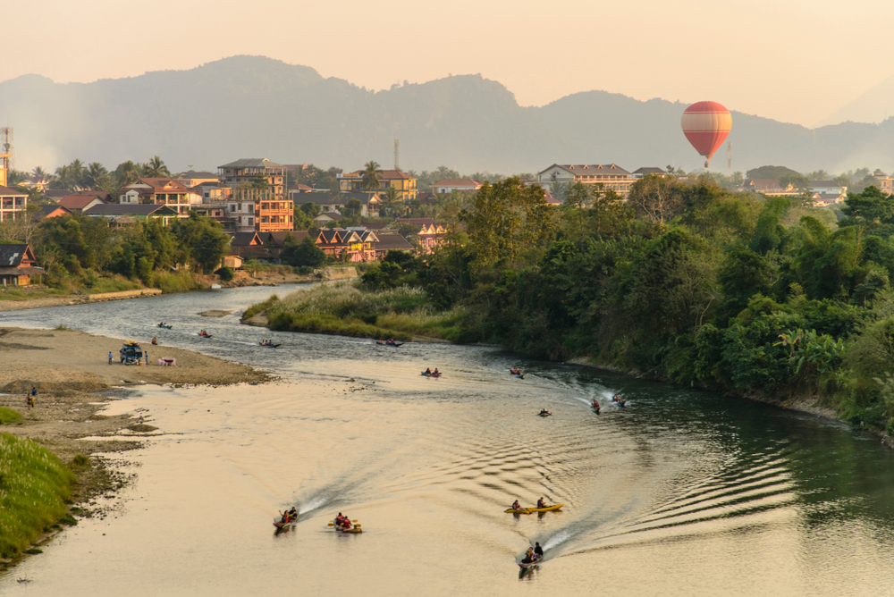 A scenic sunset view of the Vang Vieng landscape featuring the river and majestic limestone mountains.