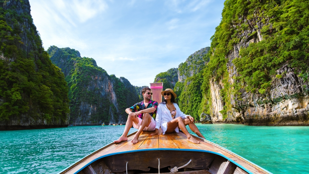 A couple enjoying a long-tail boat ride in Pileh Lagoon on a day trip from Ao Nang Beach in Krabi.