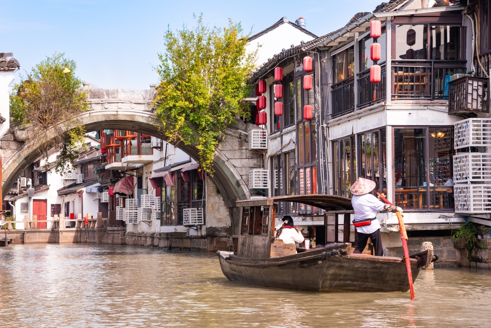 A traditional wooden boat ride under a stone arch bridge at Zhujiajiao Ancient Water Town near Shanghai.