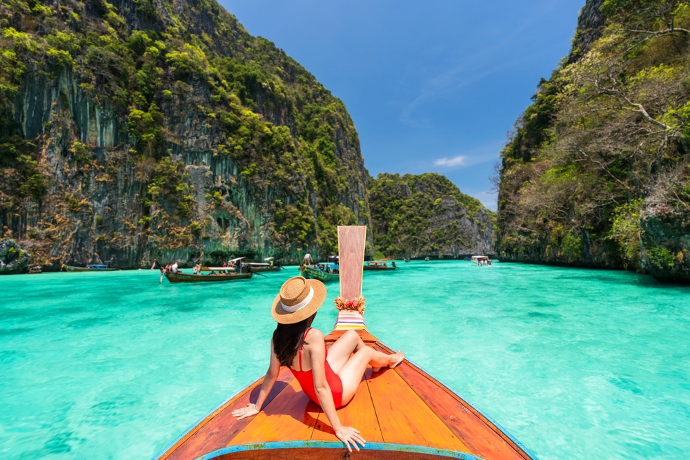 A tourist relaxing on a wooden long-tail boat during an island-hopping trip from Ao Nang Beach in Krabi.