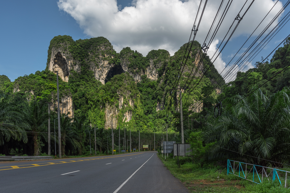 A scenic road leading toward limestone mountains and Ao Nang Beach in Krabi.